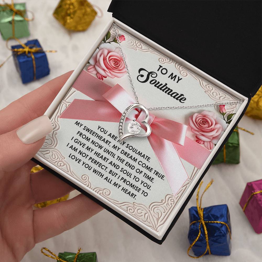 The Soulmate-Heart And Soul - Forever Love Necklace showcases interlocked hearts with a gold finish, sparkling with CZ crystals. It's displayed in an open box with a romantic message, surrounded by charming gift boxes.