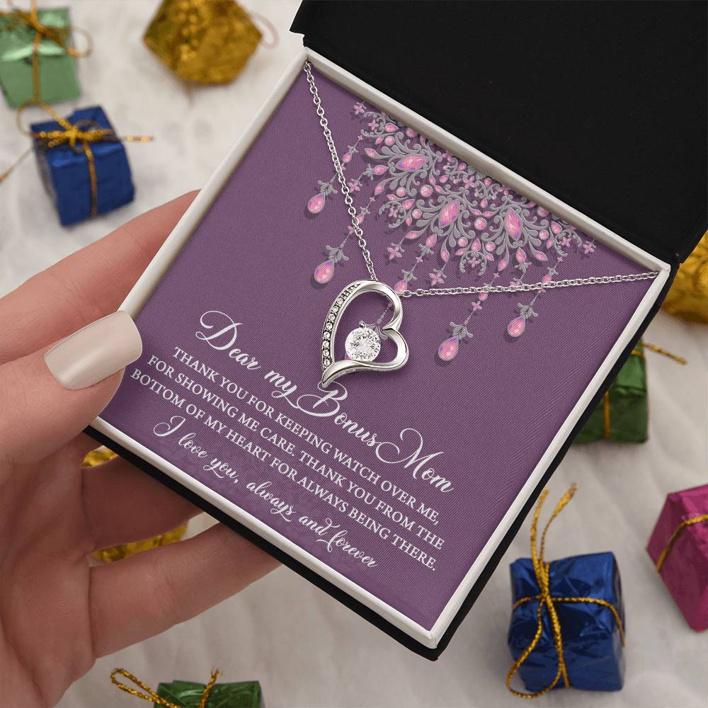 A hand holding a necklace gift box with a heart-shaped pendant and an inscription expressing gratitude to a "Bonus Mom." The stunning "To Bonus Mom, Always Being There - Forever Love Necklace," featuring a sparkling 6.5mm CZ crystal and white gold finish, gleams under the light. Wrapped presents are seen in the background.