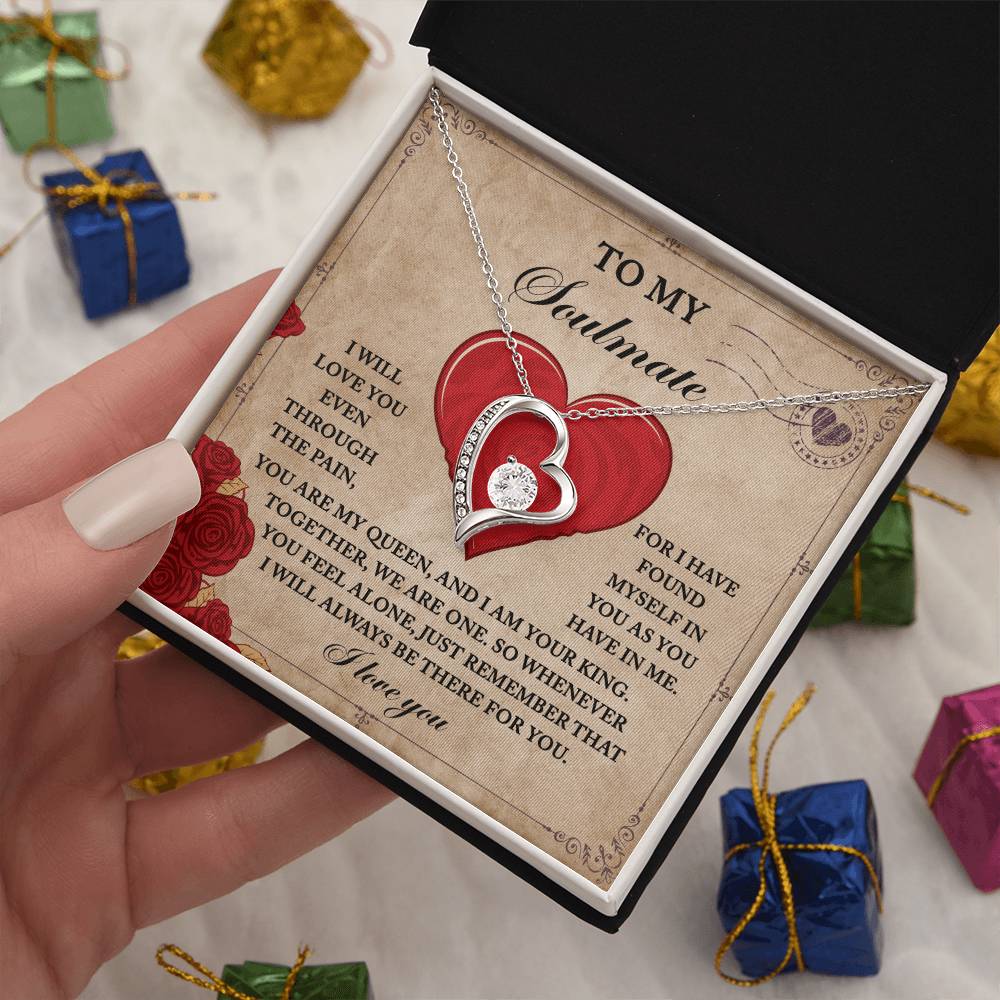 A hand presents an open gift box featuring the Soulmate-Found Myself - Forever Love Necklace in gold. Alongside it lies a card with a romantic message, enhancing the heart-shaped pendant adorned with sparkling cubic zirconia.