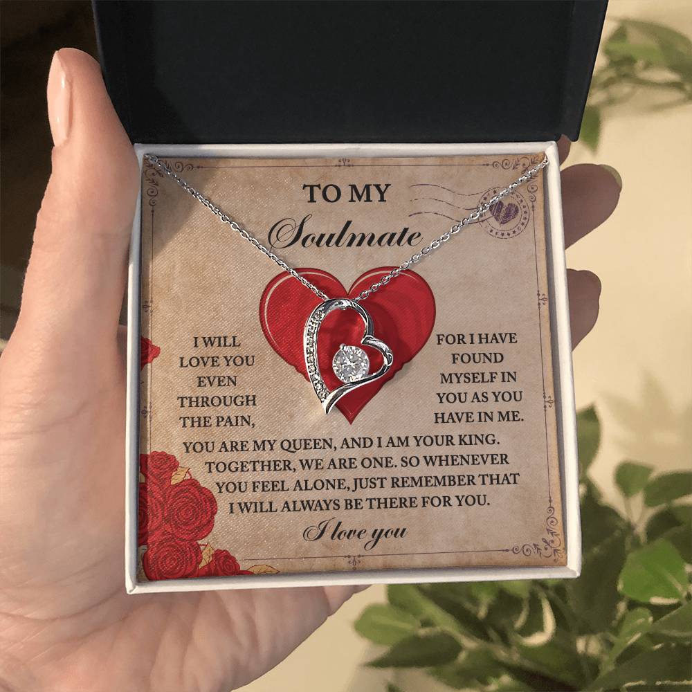 A person holds an open jewelry box featuring the Soulmate-Found Myself - Forever Love Necklace, with its heart-shaped pendant glimmering with cubic zirconia, resting on a card that shares a romantic message about being soulmates.