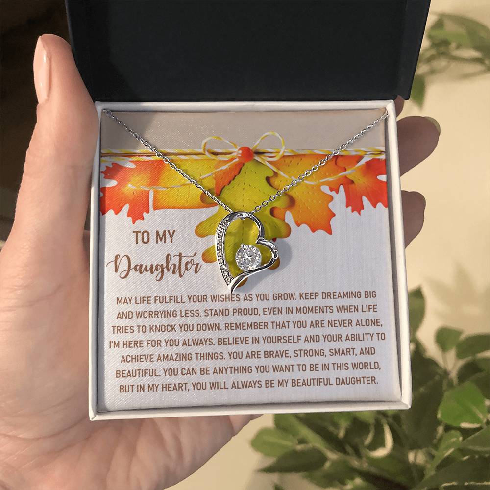 A hand holds an open gift box, unveiling the Daughter-For You Always - Forever Love Necklace with a heart-shaped charm. Accompanied by a heartfelt message card, it beautifully conveys love and encouragement to a daughter, making this gold finish necklace an unforgettable keepsake.