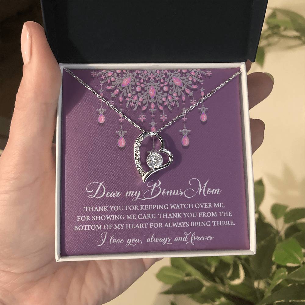 Hand holding an open jewelry box with the "To Bonus Mom, Always Being There - Forever Love Necklace" featuring a heart-shaped pendant adorned with a 6.5mm CZ crystal and a heartfelt message to a bonus mom on a purple background, expressing gratitude and love.
