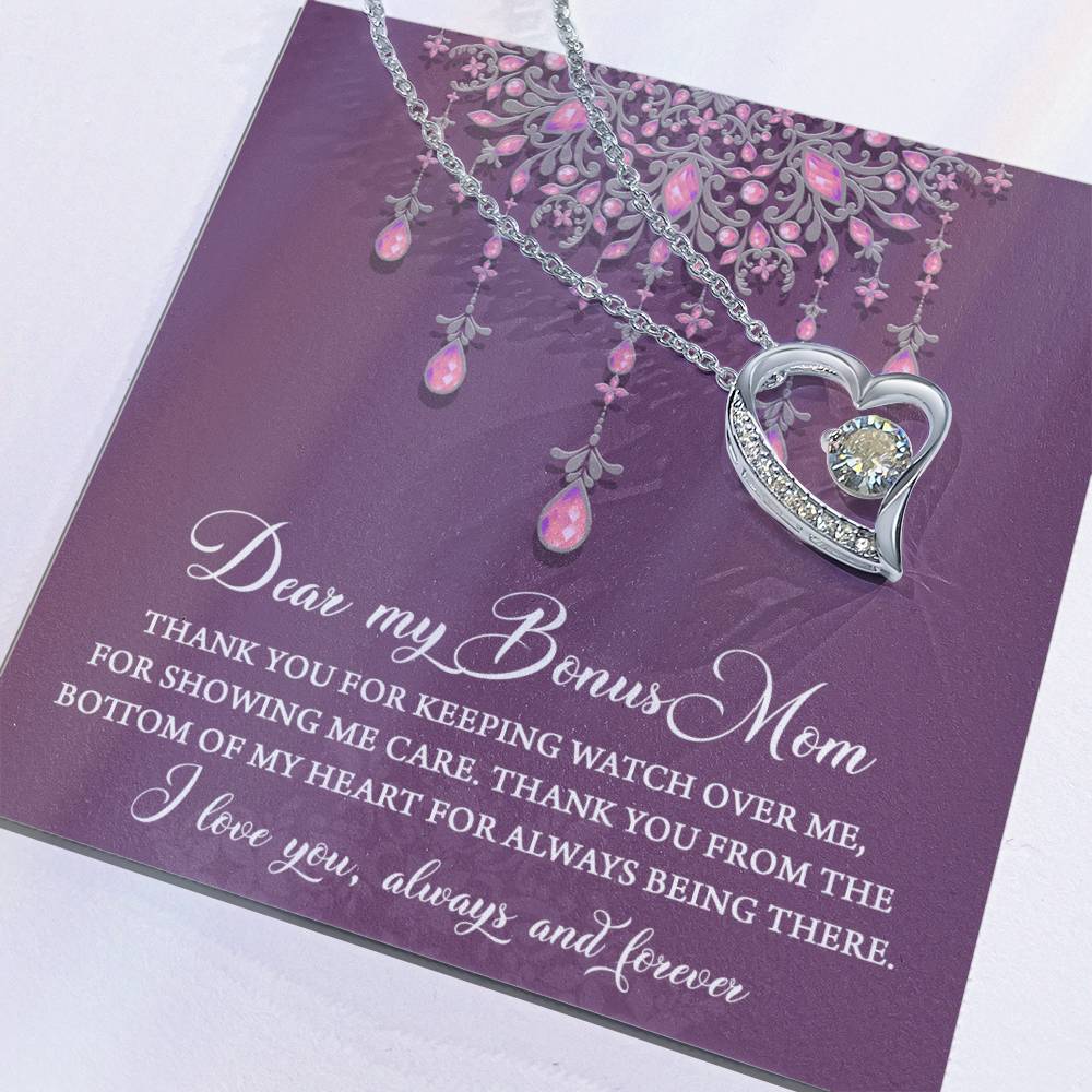 The "To Bonus Mom, Always Being There - Forever Love Necklace" is adorned with a heart-shaped pendant and placed on a card featuring a decorative design with a heartfelt message expressing gratitude to your "Bonus Mom." This exquisite necklace boasts a white gold finish and includes a dazzling 6.5mm CZ crystal, making it the ideal token of appreciation.