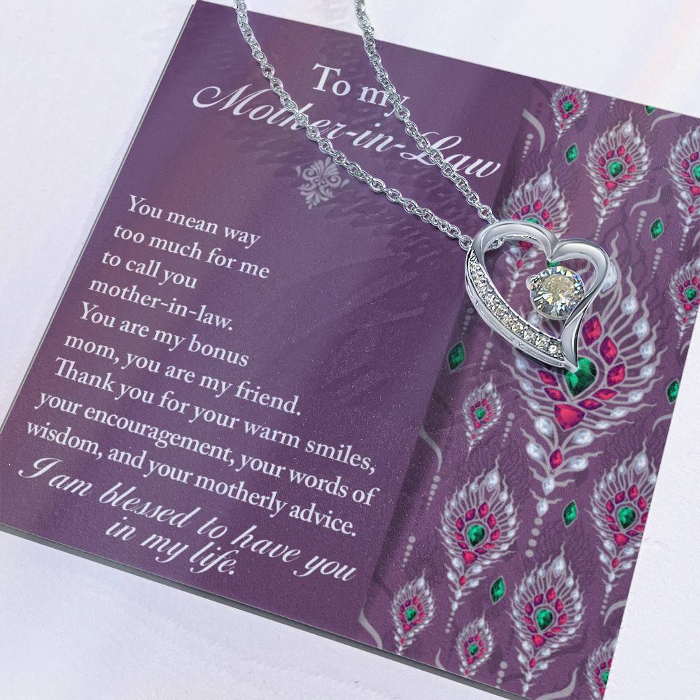 A Mother-in-Law necklace featuring a silver chain with a heart-shaped pendant and a clear gem is elegantly displayed on a card adorned with peacock feather designs and an appreciation message for your mother-in-law. This "To Mother-In-Law, Words Of Wisdom - Forever Love Necklace" is the perfect personalized gift to express your everlasting love and gratitude.