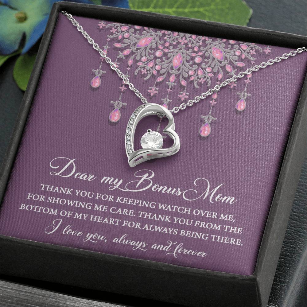 The "To Bonus Mom, Always Being There - Forever Love Necklace" is a heart-shaped pendant necklace adorned with a 6.5mm CZ crystal, elegantly displayed in a box. The liner contains a heartfelt message addressed to "Bonus Mom," expressing appreciation and love. This exquisite necklace features a stunning white gold finish, making it the perfect token of gratitude.