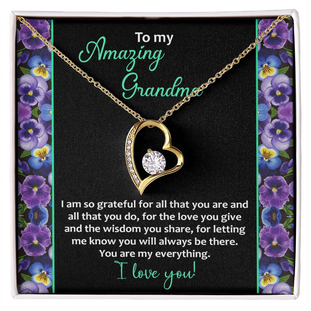 The "To Grandma, My Everything - Forever Love Necklace" comes in a 14k white gold finish, showcasing a heart-shaped pendant with a central cubic zirconia stone. The packaging beautifully expresses gratitude, love, and admiration with the message "Amazing Grandma," framed by an elegant floral border.