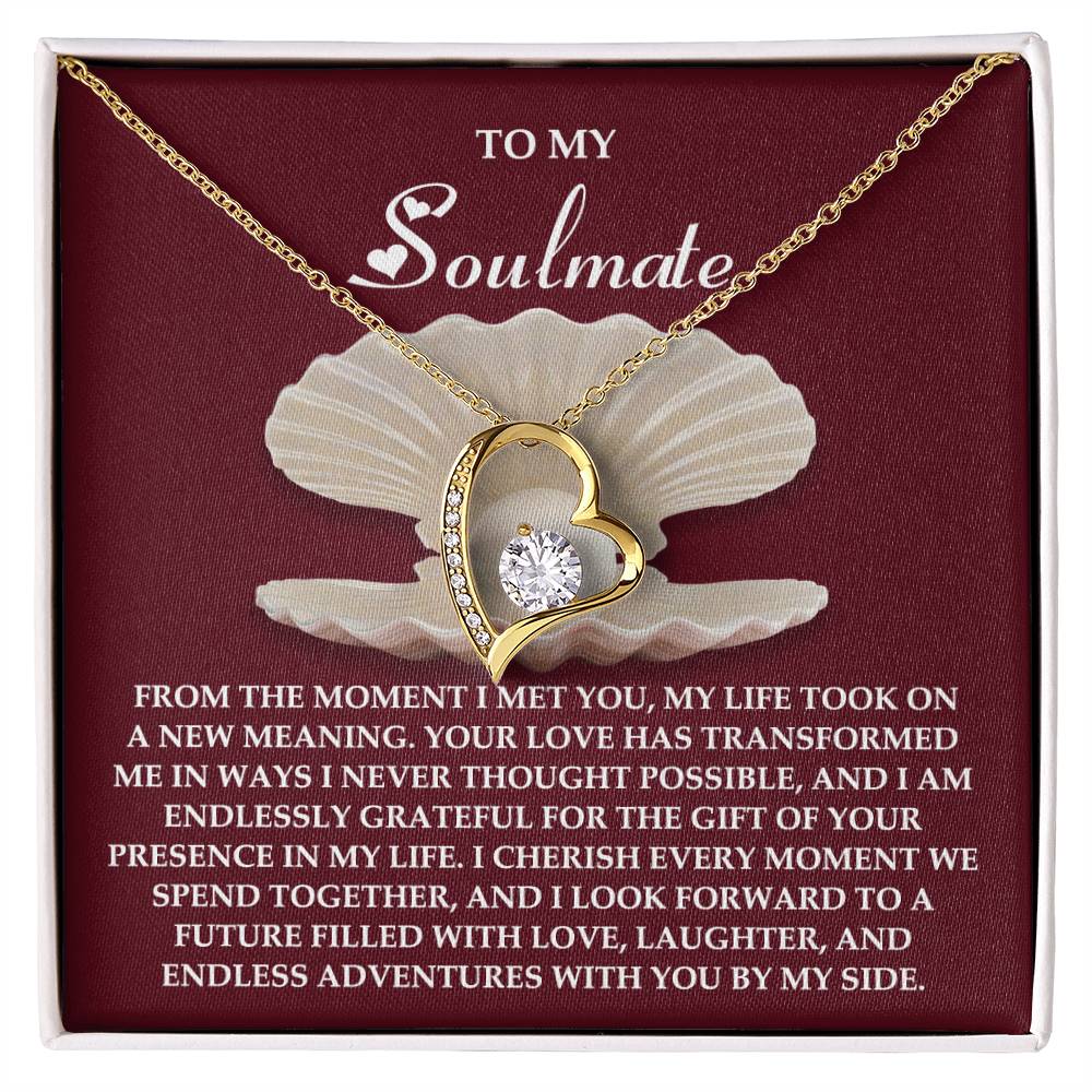The Soulmate-Every Moment - Forever Love Necklace showcases a heart-shaped gold pendant with a diamond, finished in white gold, elegantly set against a maroon card embellished with sentiments of love and gratitude.