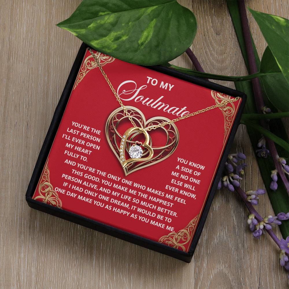 The Soulmate-The Only One - Forever Love Necklace features a heart shape with a crystal center, elegantly displayed on a red card with a soulmate message. It comes in a black box adorned with green leaves and purple flowers.