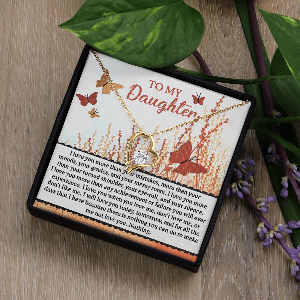 A Daughter-Love You More - Forever Love Necklace, featuring a butterfly design in gold and adorned with sparkling cubic zirconia, is elegantly placed inside a box. The accompanying card displays heartfelt messages from a parent to a daughter, surrounded by delicate floral graphics.