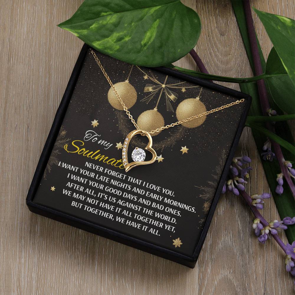 The Soulmate-Have It All - Forever Love Necklace showcases a gold heart graced with a sparkling diamond, beautifully displayed on a card inscribed with "To my Soulmate," symbolizing love and unity. The necklace is enhanced by green leaves and purple flowers, while its white gold finish offers an added touch of elegance.