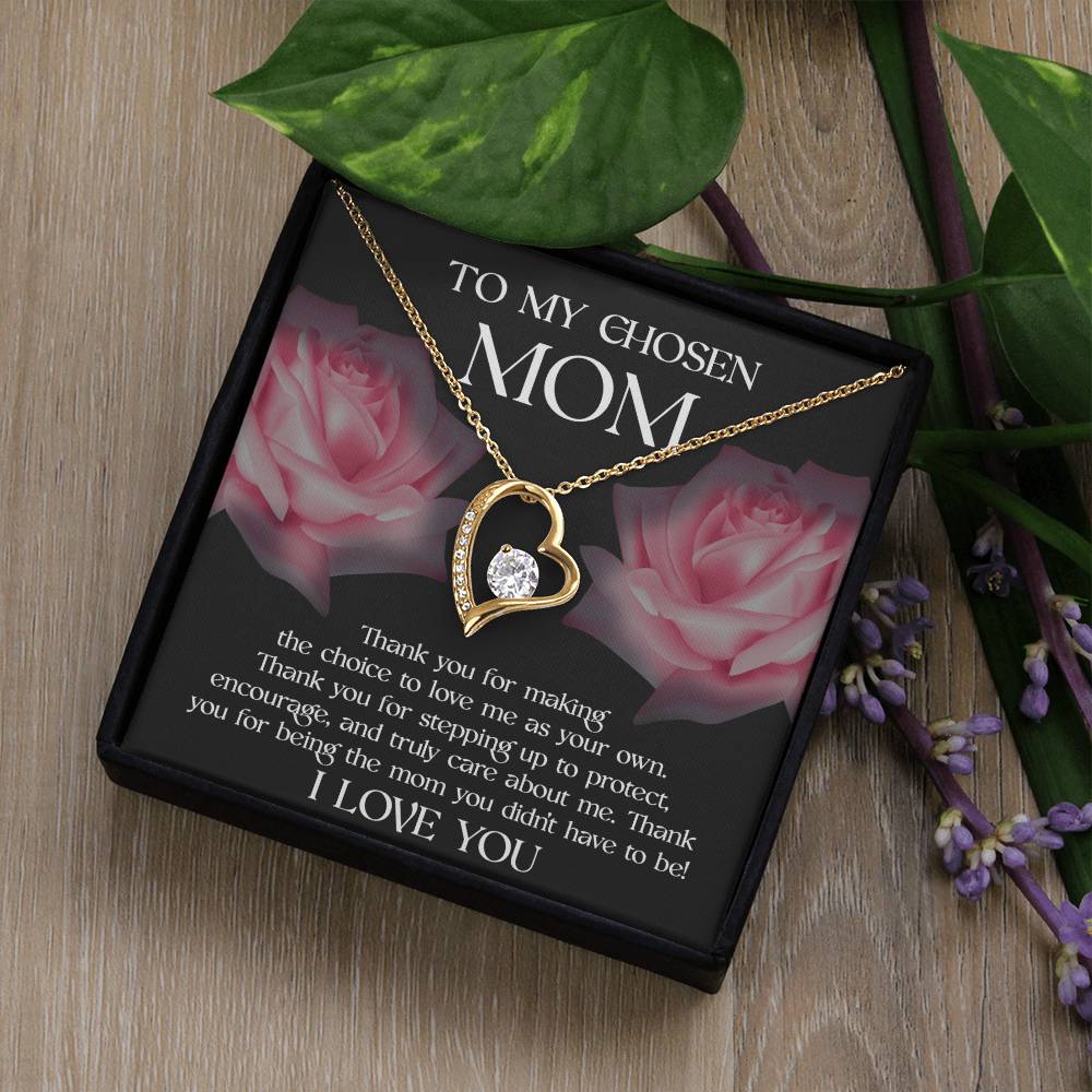 The "To Bonus Mom, My Chosen Mom - Forever Love Necklace" is an elegant heart-shaped piece featuring a central jewel. It comes in a presentation box with a heartfelt message for your chosen mother, alongside two pink rose images and green foliage in the background. This sophisticated Mother's Day gift is available in either white gold or yellow gold finish.