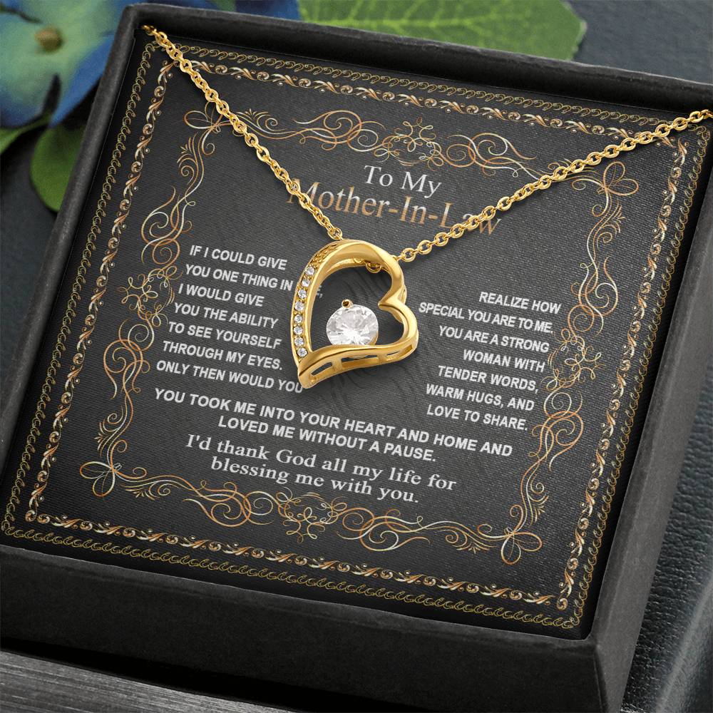 The To Mother-In-Law, Through My Eyes - Forever Love Necklace is a gold heart-shaped pendant with a central gem, elegantly presented on a black card with an ornate border. This gift conveys a heartfelt message to your mother-in-law, reflecting timeless affection and appreciation.