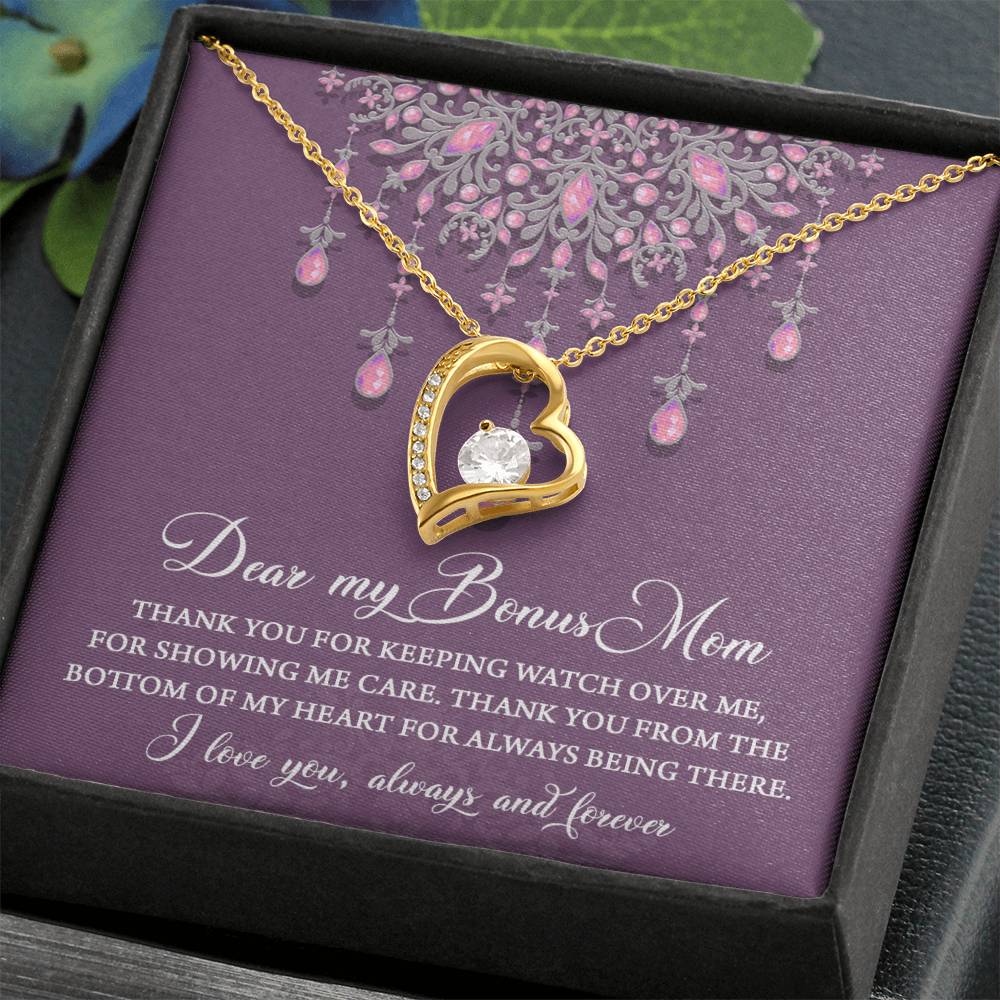 The "To Bonus Mom, Always Being There - Forever Love Necklace" features a gold heart-shaped pendant adorned with a 6.5mm CZ crystal in a white gold finish. It is elegantly presented in a black gift box against a purple background, with an accompanying card that reads, "Dear my Bonus Mom, thank you for keeping watch over me, for showing me care—thank you from the bottom of my heart for always being there. I love you, always and forever.