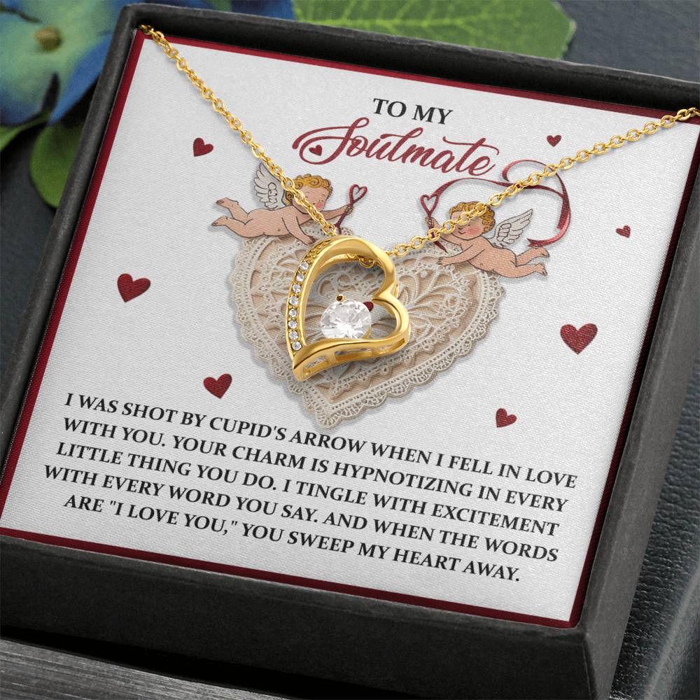 The Soulmate-Sweep My Heart - Forever Love Necklace is a gold heart-shaped piece featuring a large central CZ crystal, beautifully presented on a note adorned with romantic text, cherubs, and red hearts.