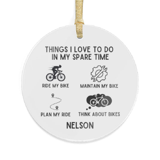 A round acrylic personalized cyclist ornament hanging on a gold ribbon. Featuring a sleek design with the words Things I love to do in my spare time that captures the essence of cycling and the custom name Nelson.