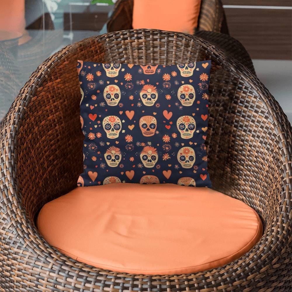 A wicker chair with an orange cushion is adorned with the Day of the Dead Mexican Skull Pillow, showcasing vibrant floral patterns that embody the spirit of Dia De Los Muertos celebrations.