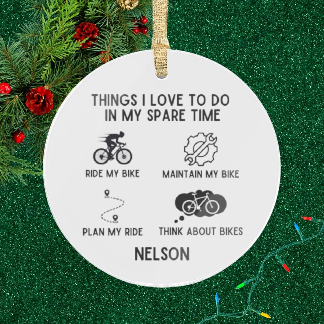 Introducing the Personalized Cyclist Ornament, a custom name transparent acrylic piece that humorously lists favorite cycling activities: "Things I love to do in my spare time: ride my bike, maintain my bike, plan my ride, think about bikes." Decorated with festive holiday greenery and twinkling lights, it's the ideal gift for bike enthusiasts and cycling lovers.