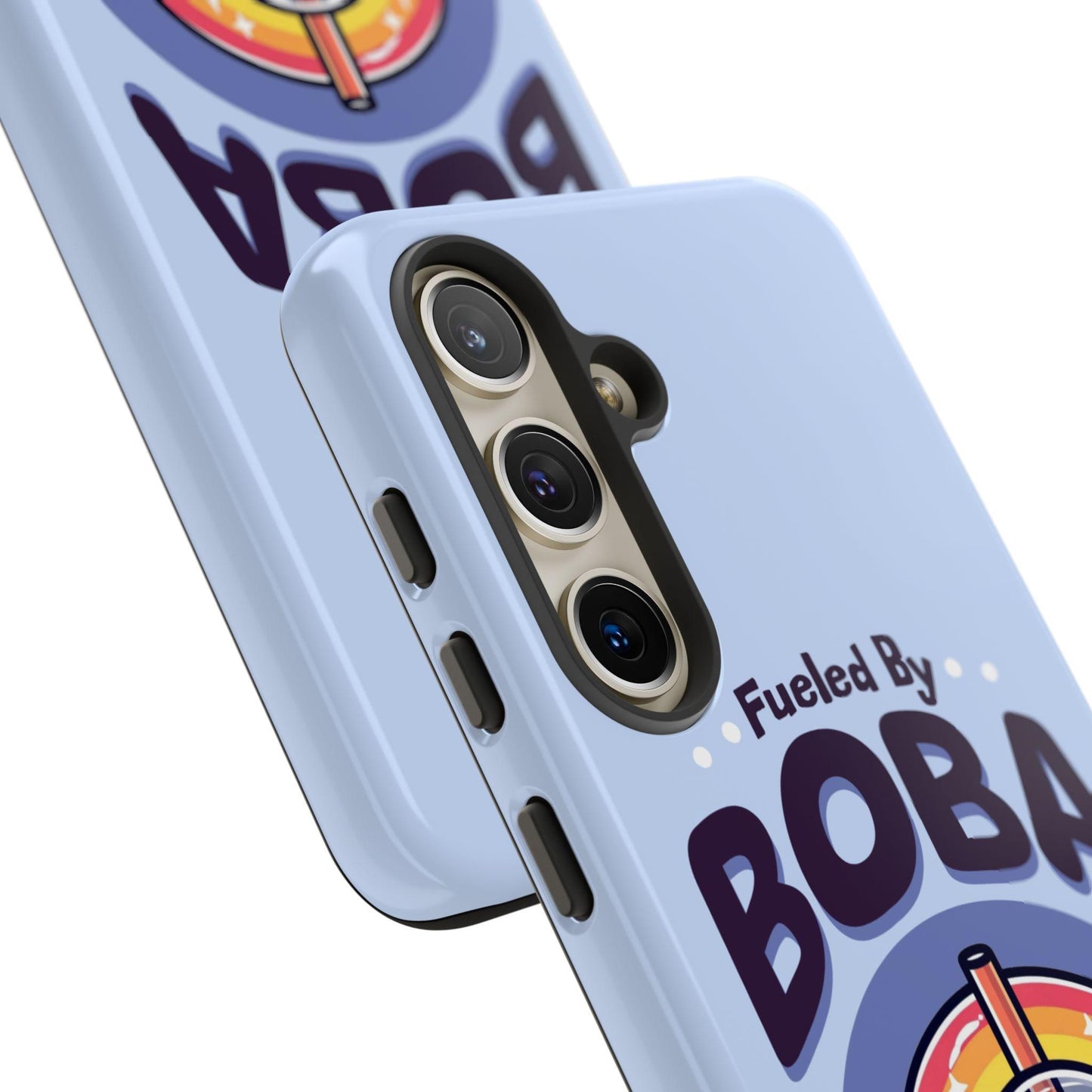 Close-up of two Cute boba phone cases emblazoned with the text "Fueled By BOBA" and featuring an illustration of a boba tea cup. These adorable cases, designed for phones like the iPhone 16 Pro Max, 15, 14, 13 and Samsung Galaxy Pixel models, include precise camera cutouts for phones with three lenses—perfect as a birthday or Christmas gift for boba lovers.