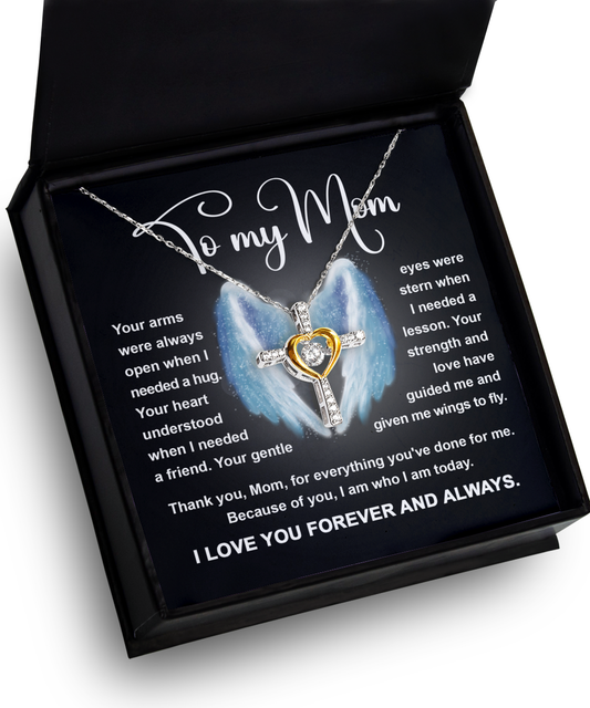 A heart-shaped To Mom, Wings To Fly - Cross Dancing Necklace in a gift box with a message to a mother printed on the interior lid.
