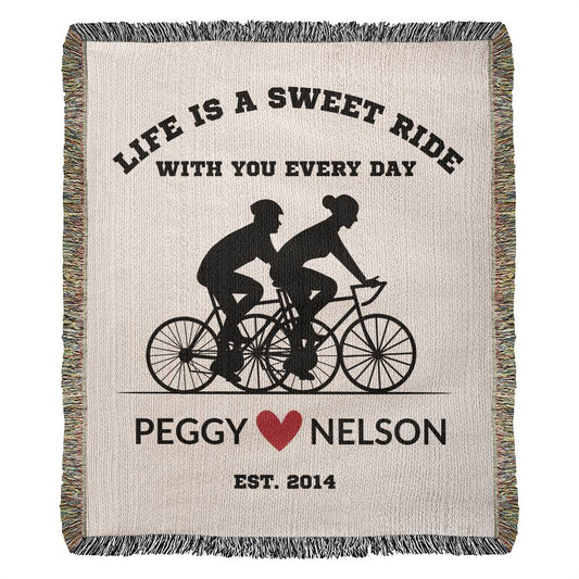 This personalized heirloom woven blanket, featuring a cycling couple silhouette, is inscribed with: "Life is a sweet ride with you every day. Peggy ♥ Nelson. Est. 2014.