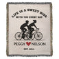 This personalized heirloom woven blanket, featuring a cycling couple silhouette, is inscribed with: "Life is a sweet ride with you every day. Peggy ♥ Nelson. Est. 2014.