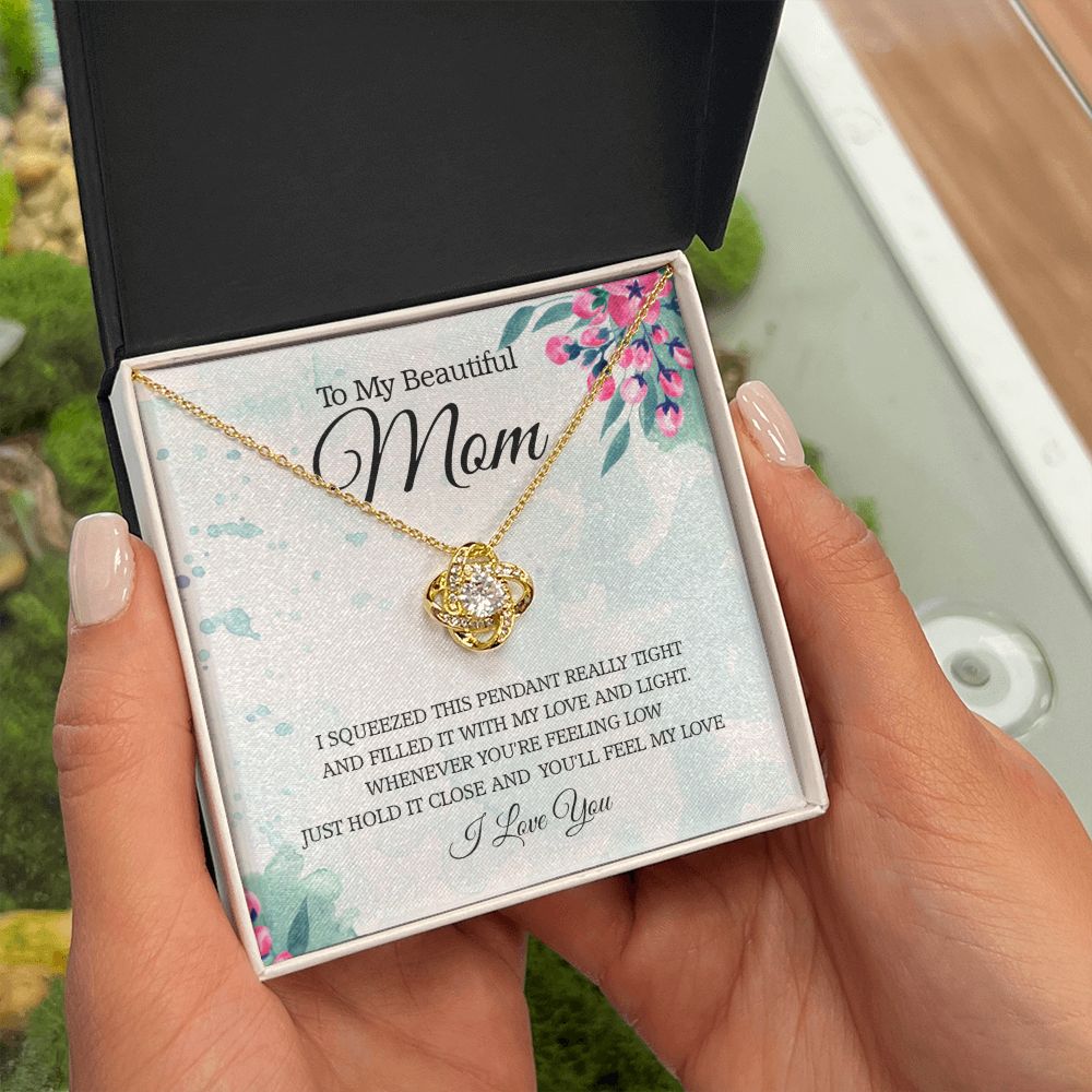 A person holding a gift box with the I Squeezed This Pendant Love Knot Necklace - For Mom, by ShineOn Fulfillment, in it.