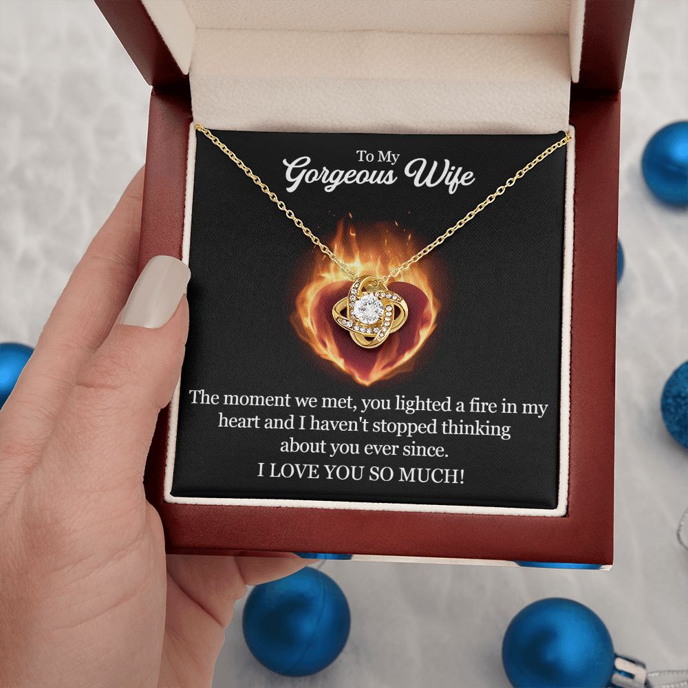 A woman holding a ShineOn Fulfillment "The Moment We Met Love Knot Necklace - To Wife from Husband" in a box.