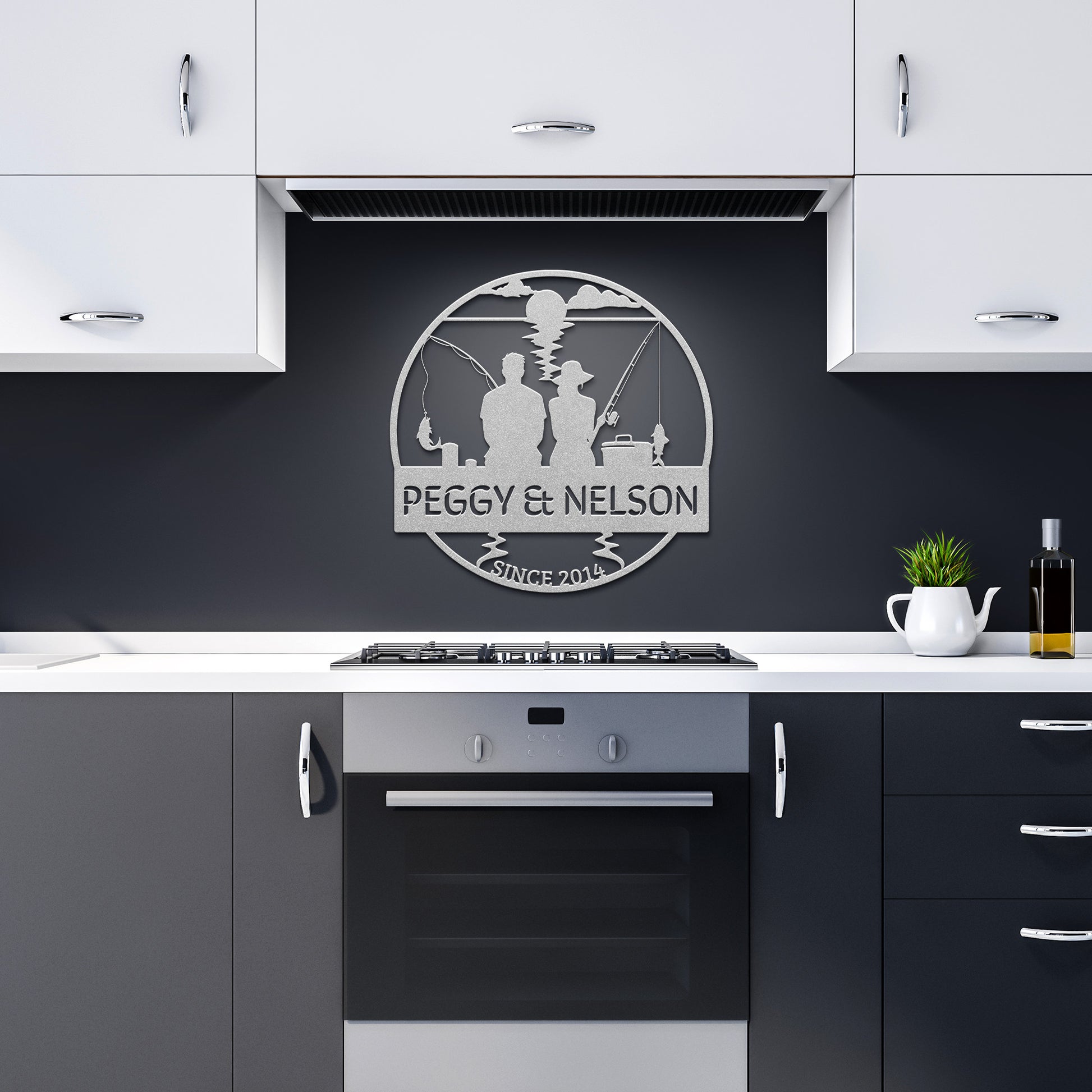 A modern kitchen with white upper cabinets and gray lower cabinets. A black backsplash features the elegant "Couple Fishing Together Metal Wall Art" sign with "Peggy & Nelson, Since 2015" above the stove, adding a touch of timeless home decor to the space.