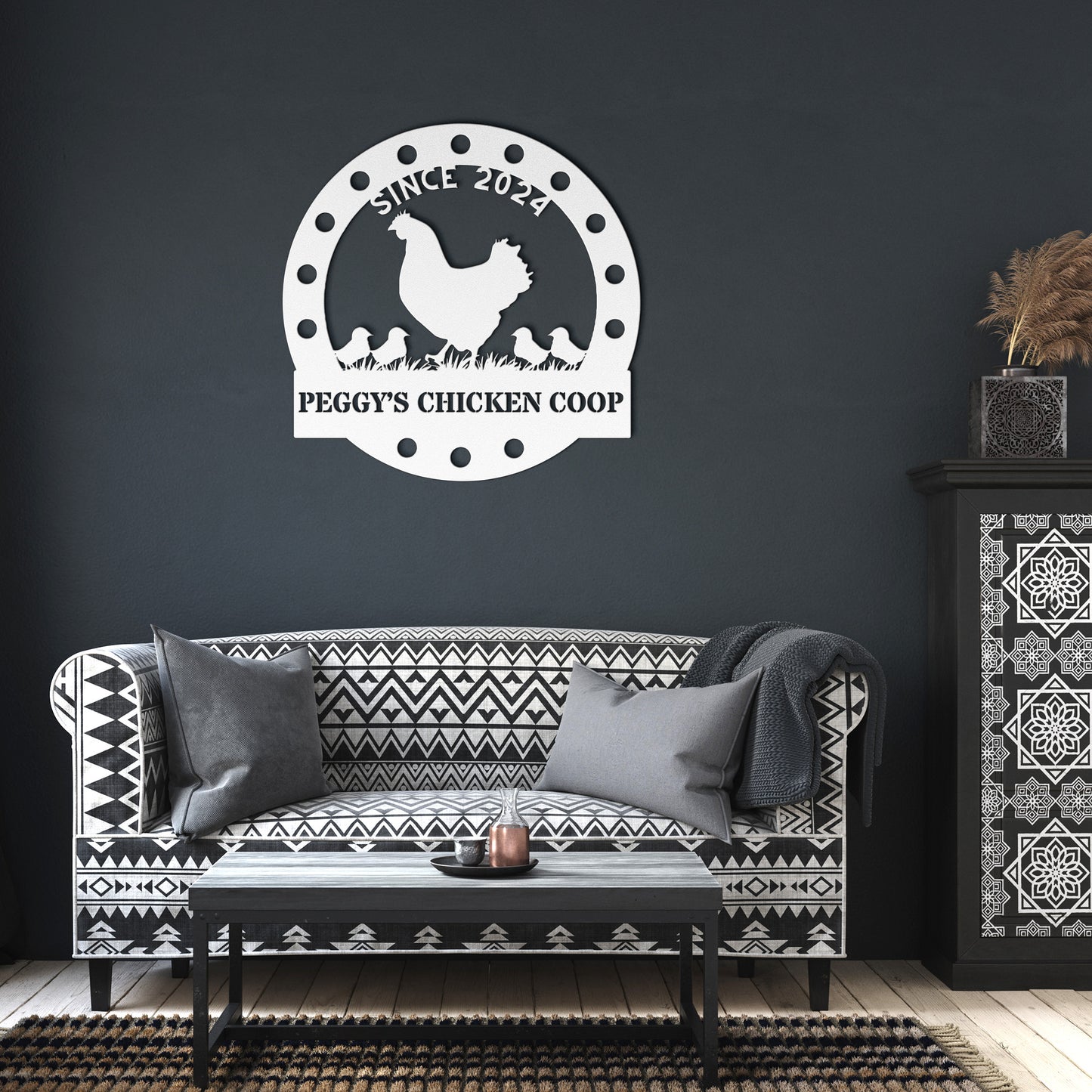 The "Custom Chicken Coop Metal Sign," made from 18-gauge steel, hangs above a patterned sofa with cushions, alongside a small table and decorative cabinet on a dark wall.