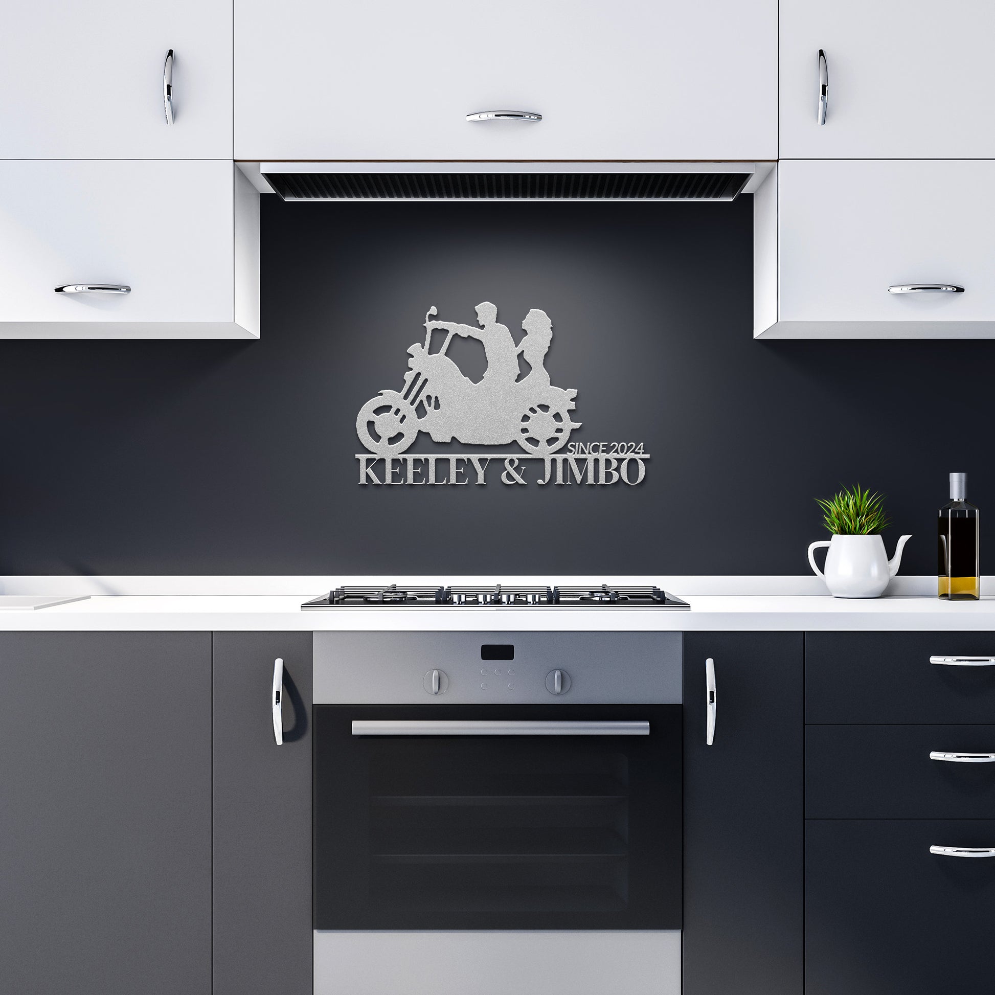 A modern kitchen with black and white cabinets features the Custom Motorcycle Couple Metallic Wall Art above the stove, depicting a couple on a motorcycle with "Keeley & Jimbo Since 2024," adding an edgy touch to the decor.