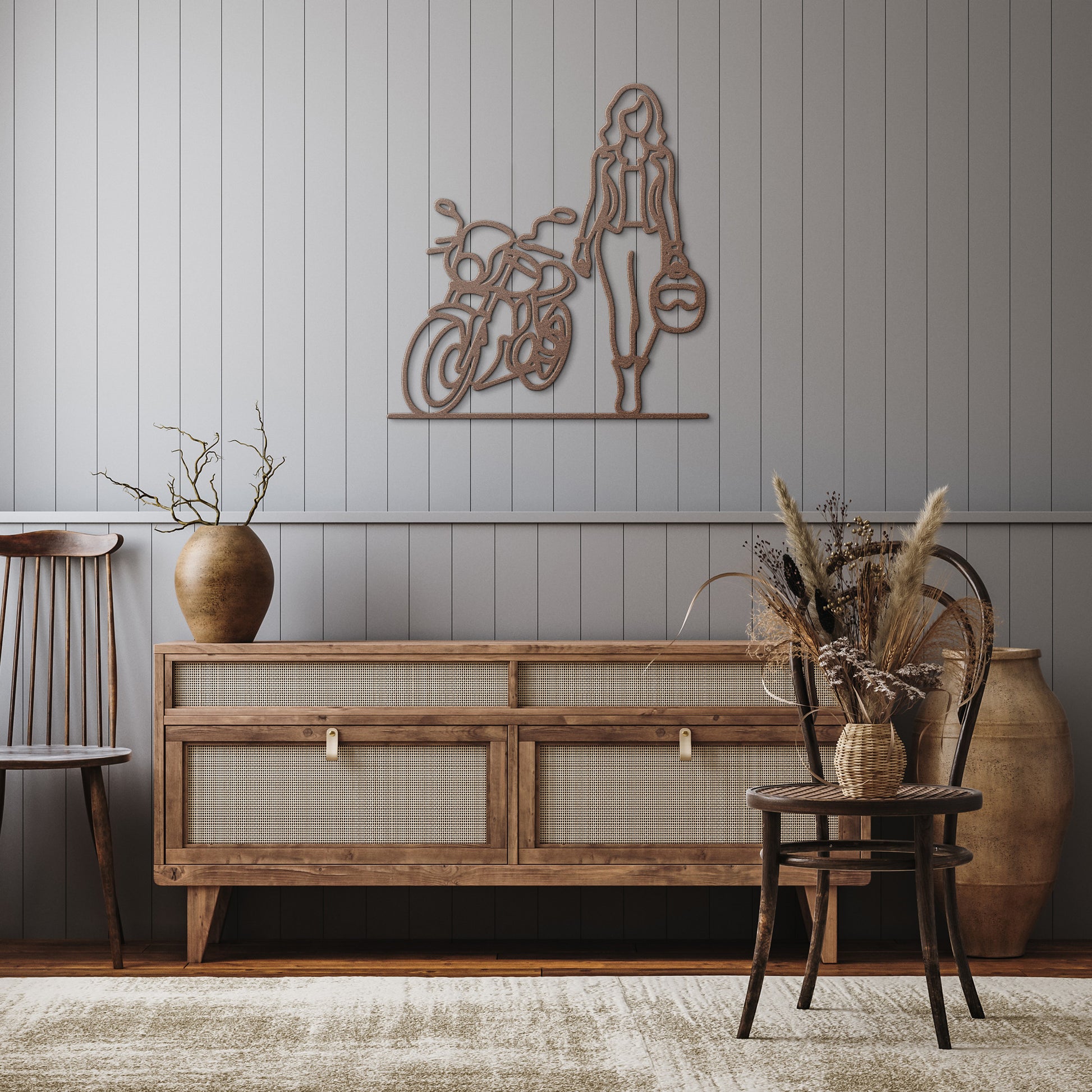 In a minimalist living room, wooden furniture includes a large vase and the striking FEMALE BIKER LINE ART wall piece. Dried plants in vases complement the home decor, with a sleek powder-coated metal sign adding an industrial touch.