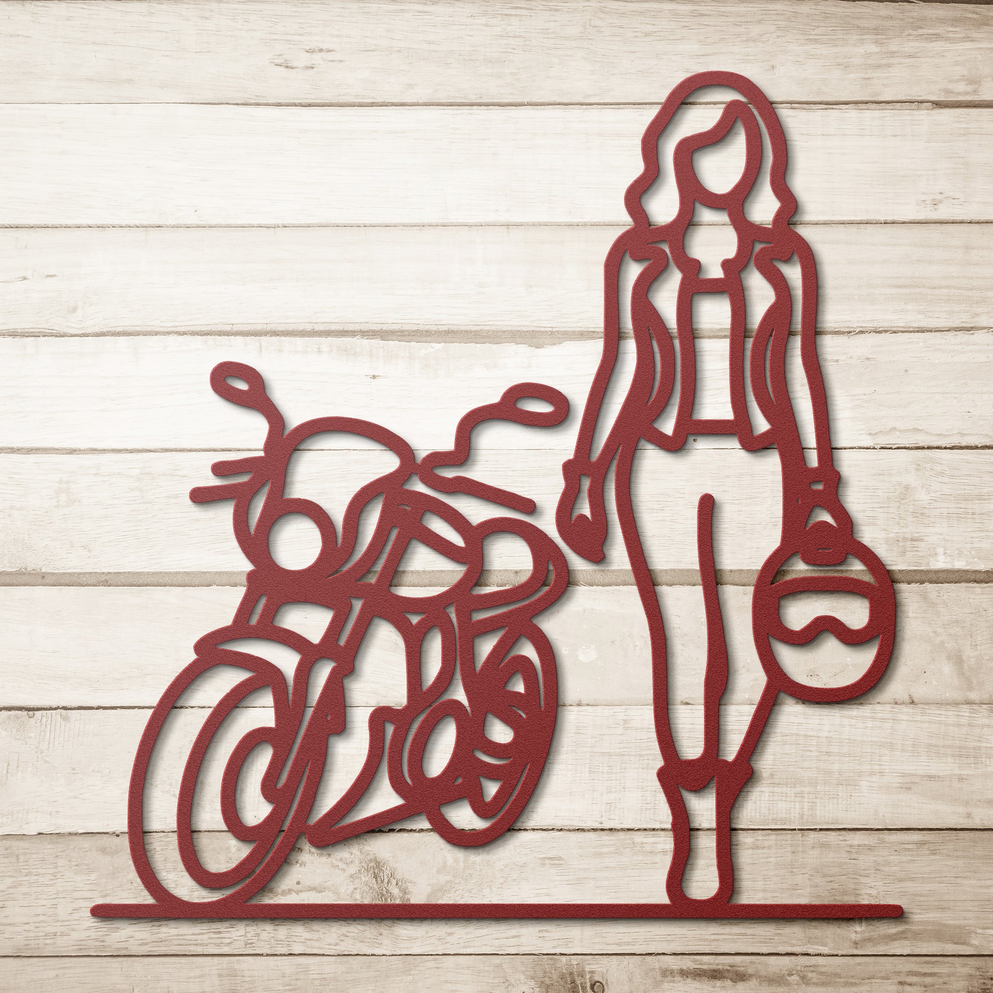 The FEMALE BIKER LINE ART, a striking piece made from powder-coated red metal, features the silhouette of a person holding a helmet beside a motorcycle, set against a light wooden background—an ideal addition to any home decor.