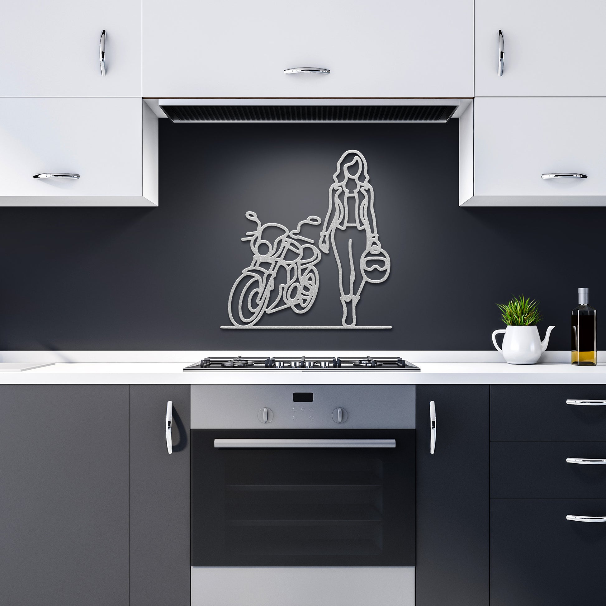 A modern kitchen featuring black and white cabinets, the "FEMALE BIKER LINE ART" powder-coated metal sign as sophisticated wall art, and a plant next to a bottle of olive oil on the counter enhances the home decor.