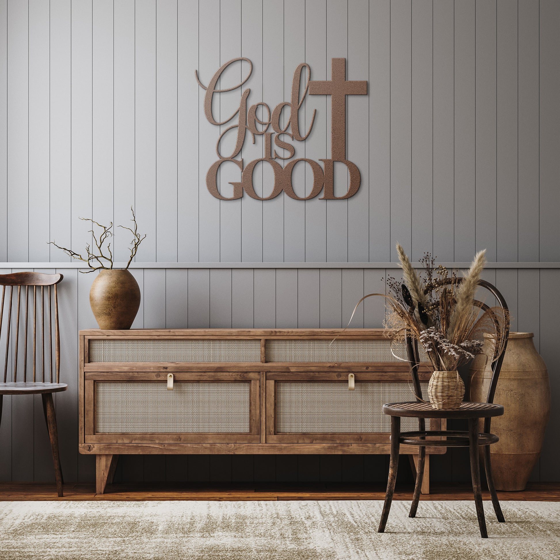 A wooden sideboard with a vase, dried plants, and two chairs complements this serene space. The "God Is Good Christian Metal Art," crafted from 18 gauge steel and featuring the words "God is Good" next to a cross, adds elegance to the neutral color scheme in your home decor.