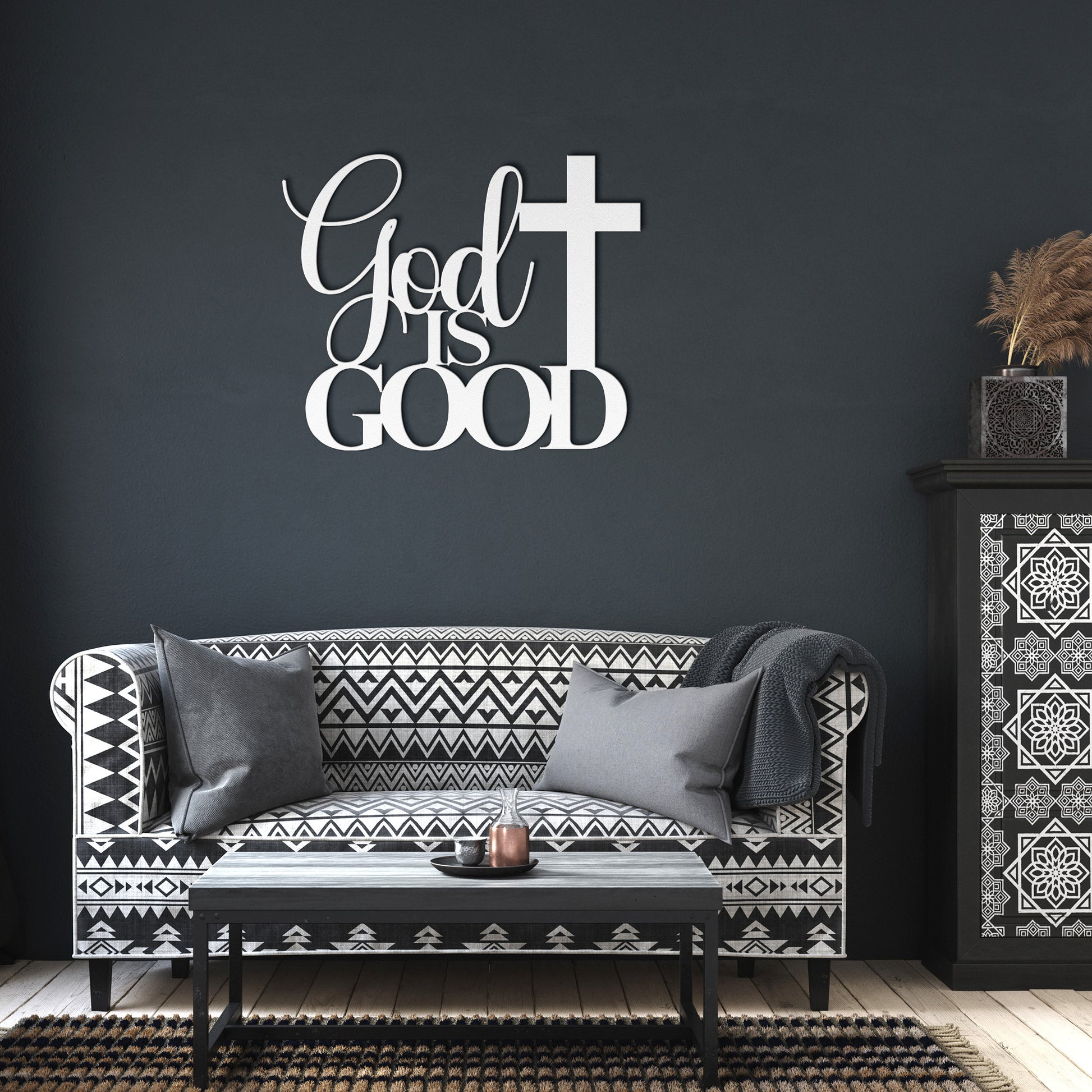 A brown wooden door with decorative glass is set in a brick wall. A potted plant sits beside it, and a stylish powder-coated sign "God Is Good Christian Metal Art" next to a cross enhances the decor. A black outdoor lamp hangs above the sign, completing the charming home decor scene.