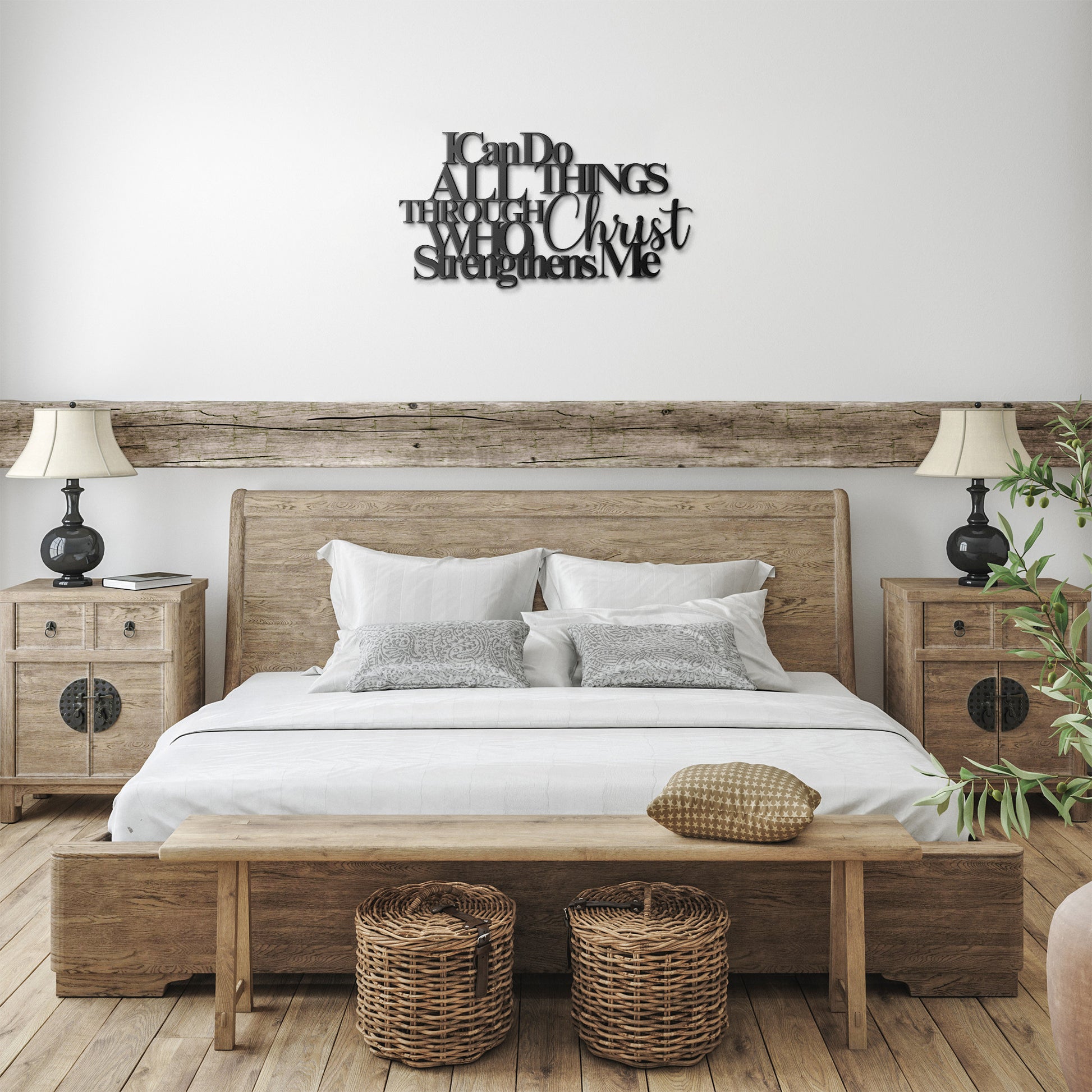A bedroom features a wooden bed with white bedding, two bedside tables with lamps, and an "I Can Do All Things Through Christ Who Strengthens Me" Christian metal sign above the bed. Two wicker baskets are placed in front of the bench, completing this inviting home decor setup.