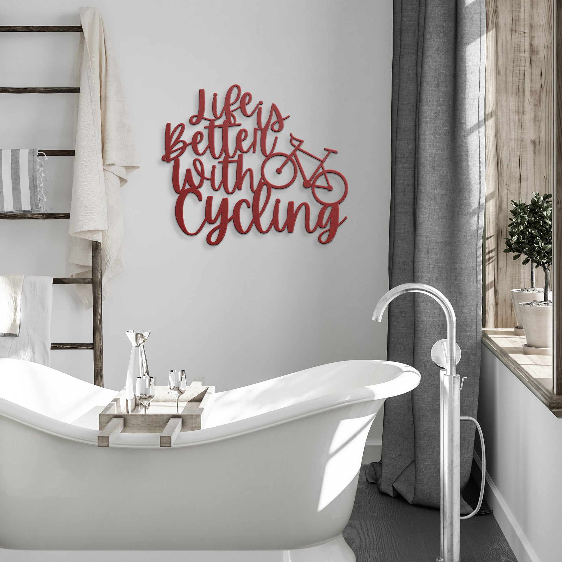 A brick wall with a wooden door, a potted plant, a black outdoor light, and the "Life is Better with Cycling Metal Sign - Road Bike Edition," reading "Life's Better with Cycling" alongside a bicycle graphic, perfect for stylish home decor.