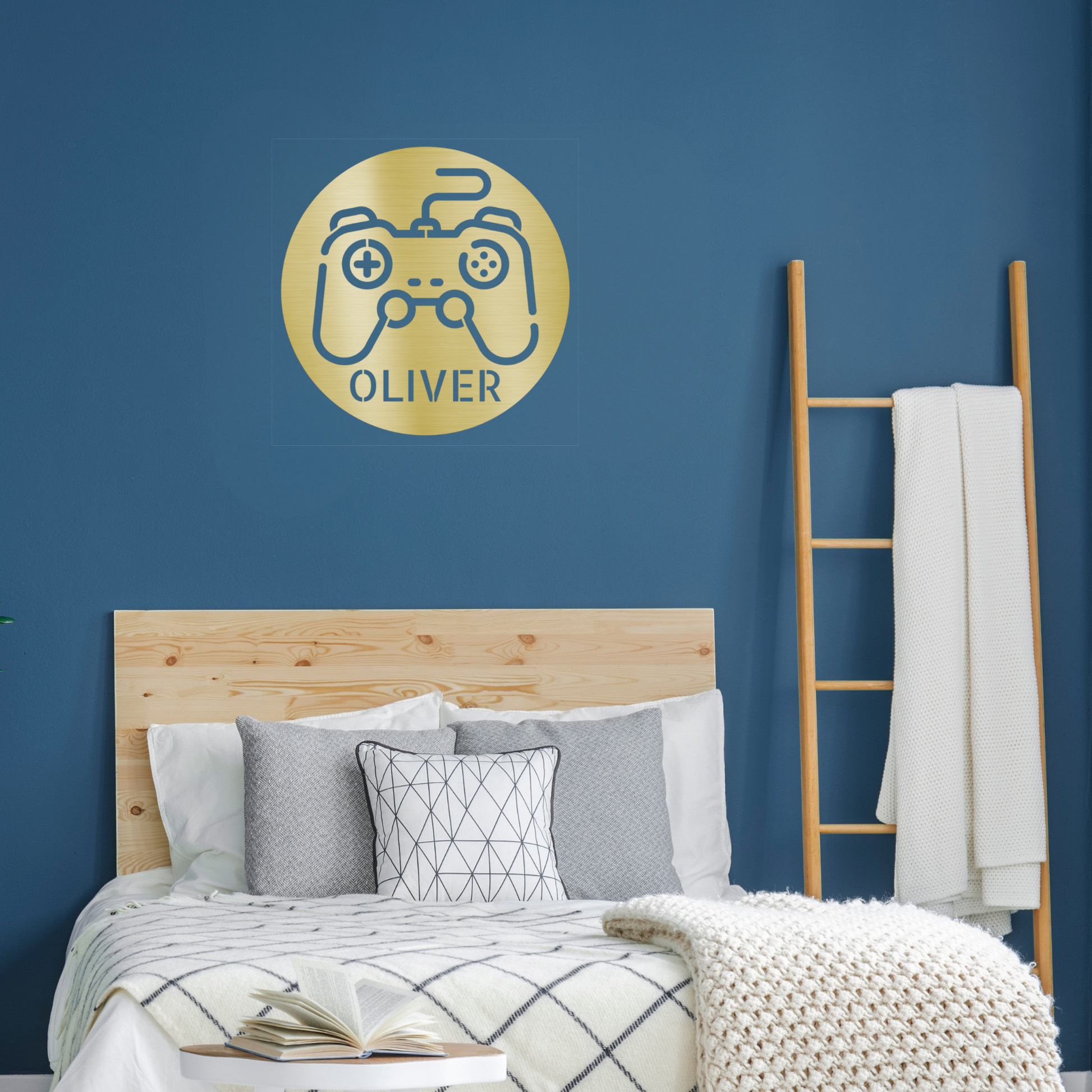A bedroom with a wooden bed, blue walls, a blanket ladder, and a Personalized Gamer Controller Metal Sign featuring "OLIVER" above the bed.