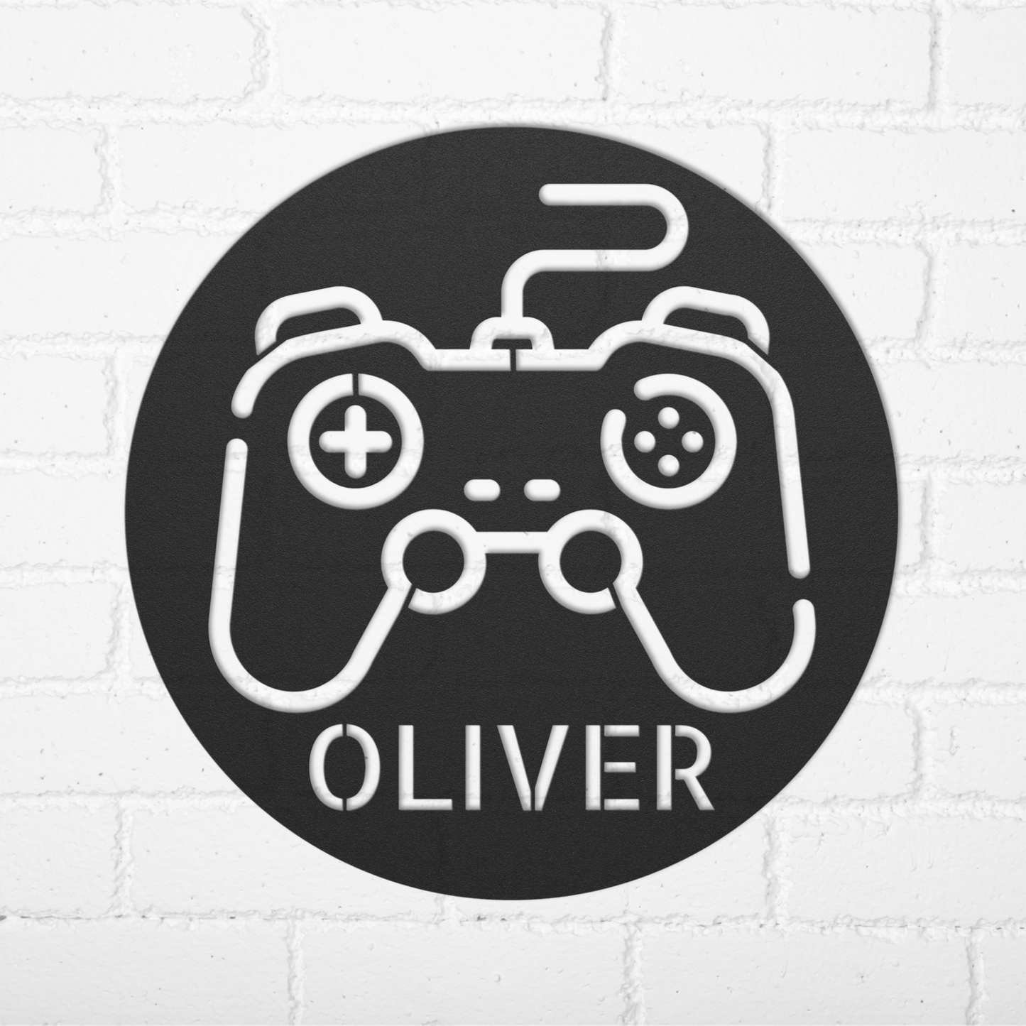 The Personalized Gamer Controller Metal Sign is a round black customizable metal art piece with a white video game controller outline and "OLIVER" in bold letters—ideal as unique wall decor.