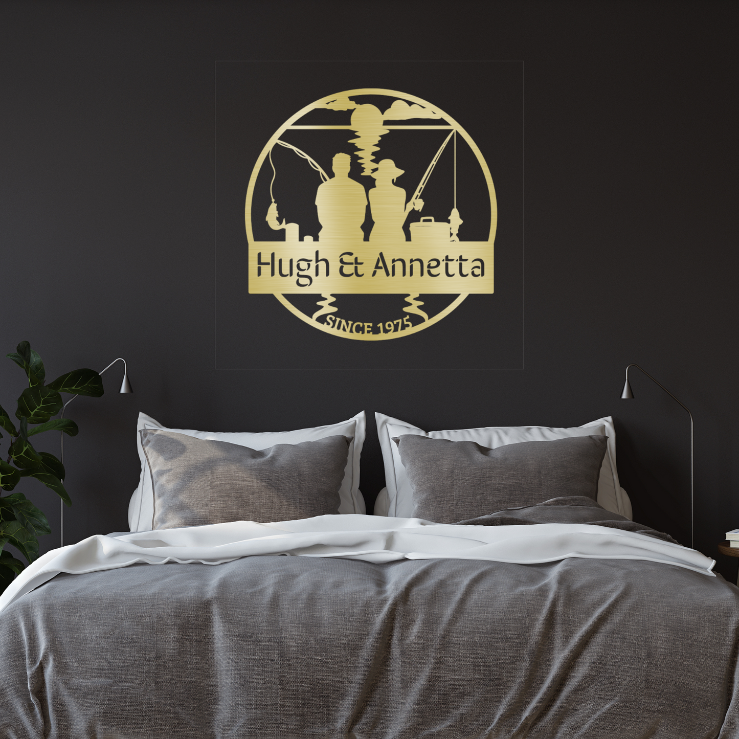 A cozy bedroom with gray and white bedding features a plant and a Custom Fishing Couple Metal Sign above the bed, personalized with "Hugh & Annetta" and "Since 1975," making it a perfect fishing anniversary gift.