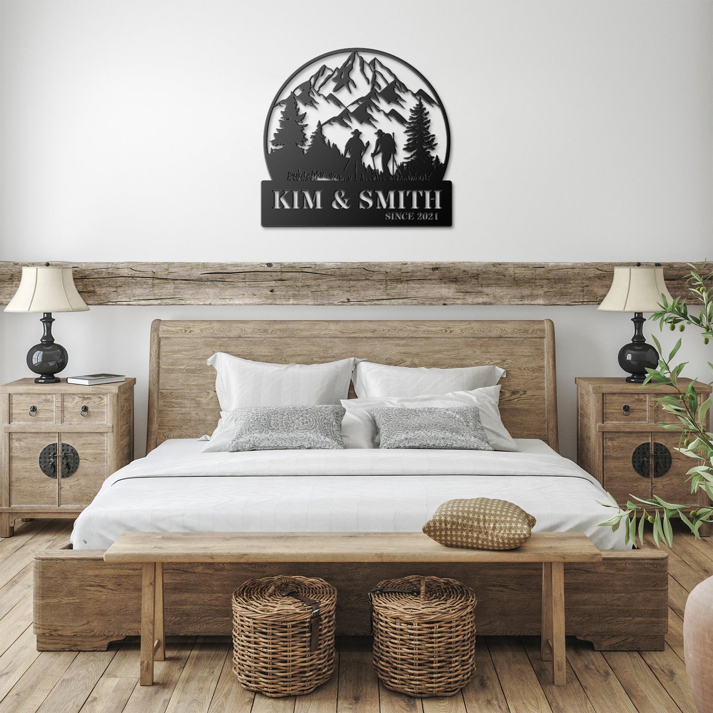 A brick house exterior with a wooden door, arched stained glass, wall-mounted lamp, potted flowers, and an 18 gauge steel decor sign reading "Kim & Smith," featuring the Updated Hiking Couple Metal Art with a mountain and tree silhouette that serves as a timeless piece of home decor.
