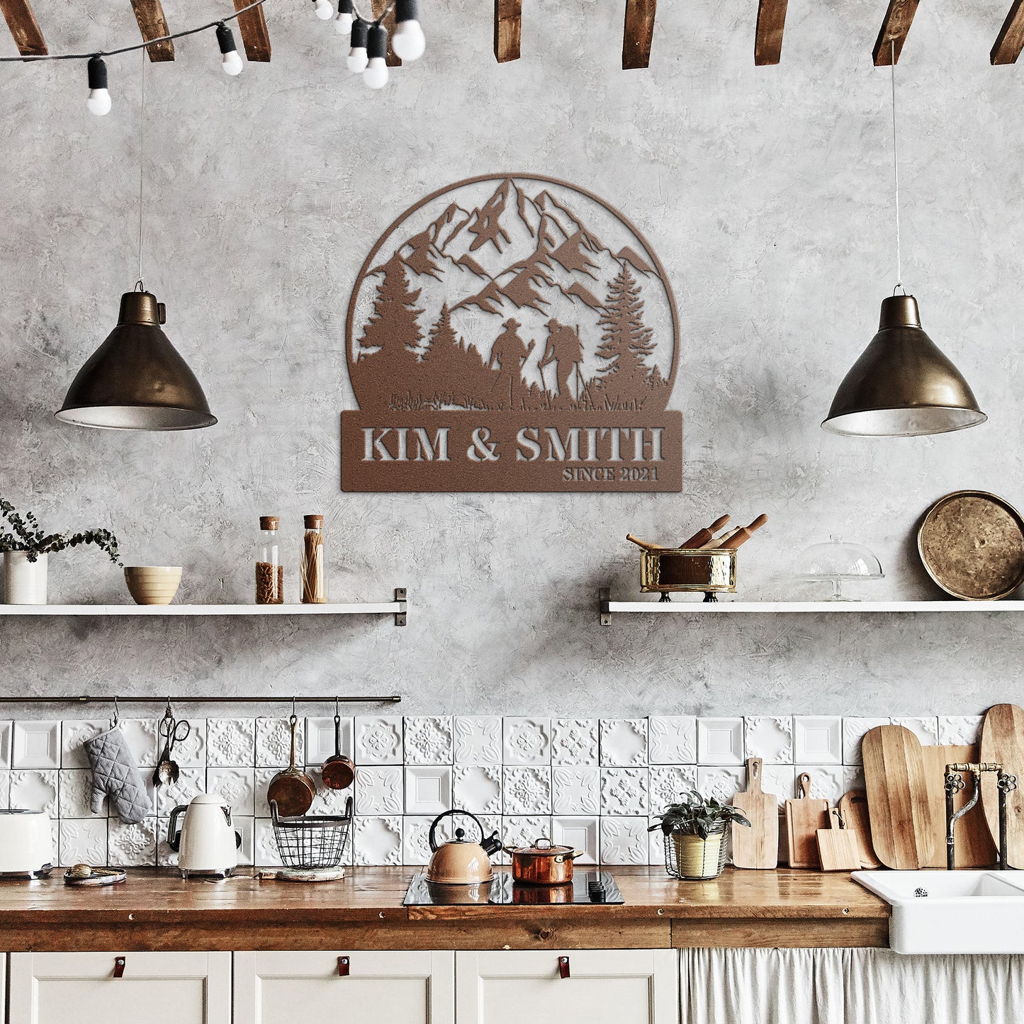 A brick house exterior with a wooden door, arched stained glass, wall-mounted lamp, potted flowers, and an 18 gauge steel decor sign reading "Kim & Smith," featuring the Updated Hiking Couple Metal Art with a mountain and tree silhouette that serves as a timeless piece of home decor.