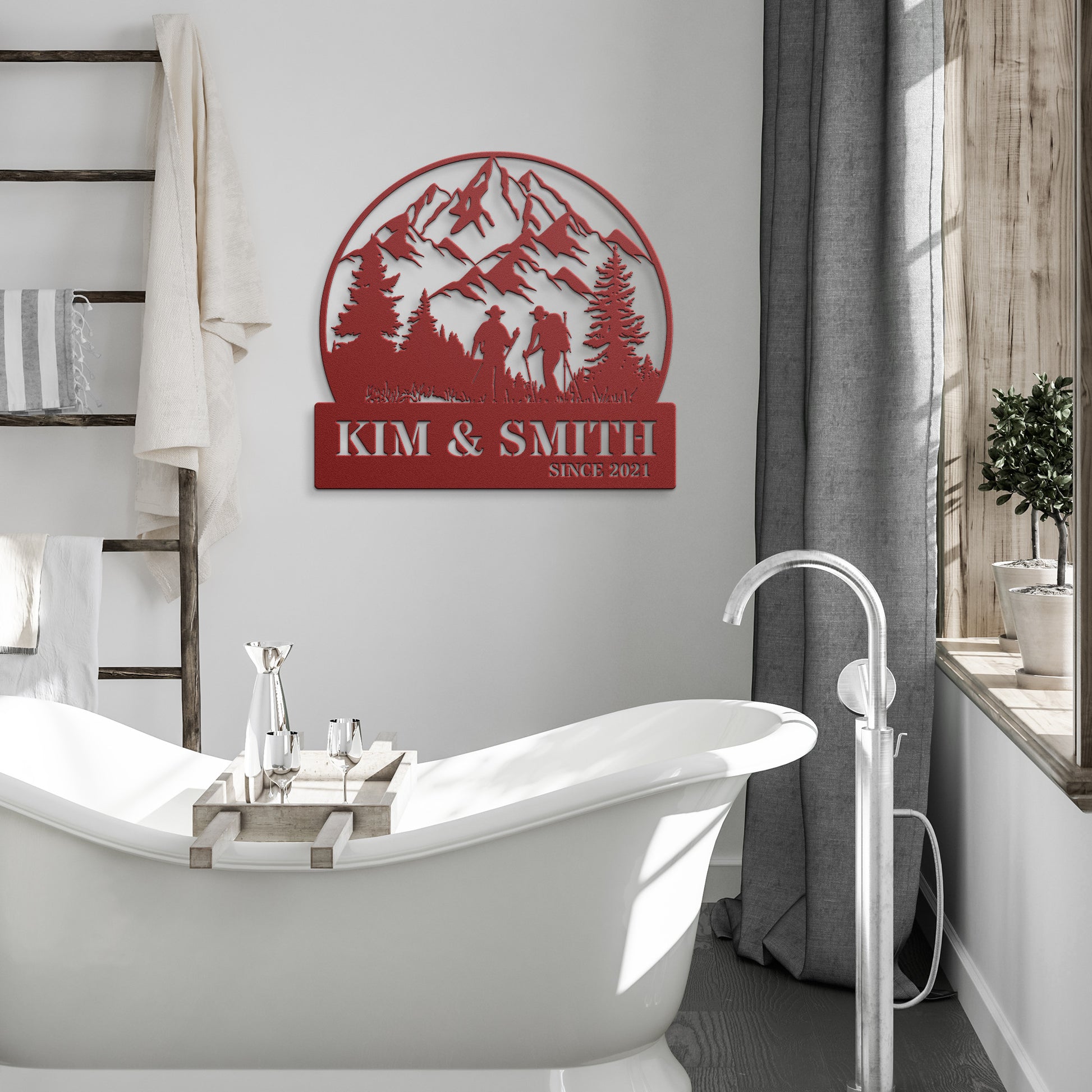 A brick house exterior with a wooden door, arched stained glass, wall-mounted lamp, potted flowers, and an 18 gauge steel decor sign reading "Kim & Smith," featuring the Updated Hiking Couple Metal Art with a mountain and tree silhouette that serves as a timeless piece of home decor.