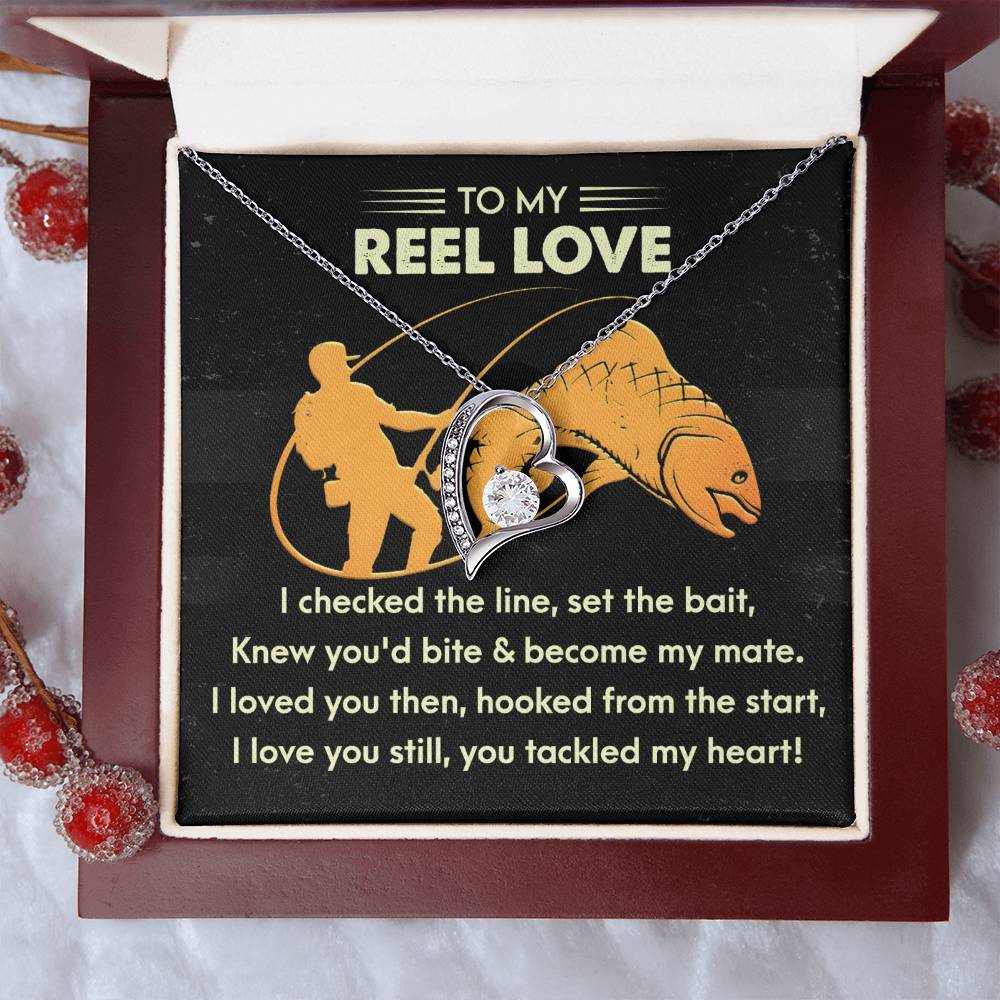 The Soulmate-Tackled My Heart - Forever Love Necklace showcases a gold heart-shaped pendant with CZ crystal, nestled in a box. Behind it, a note with fishing imagery and affectionate text celebrates timeless devotion. Ideal for that special someone.