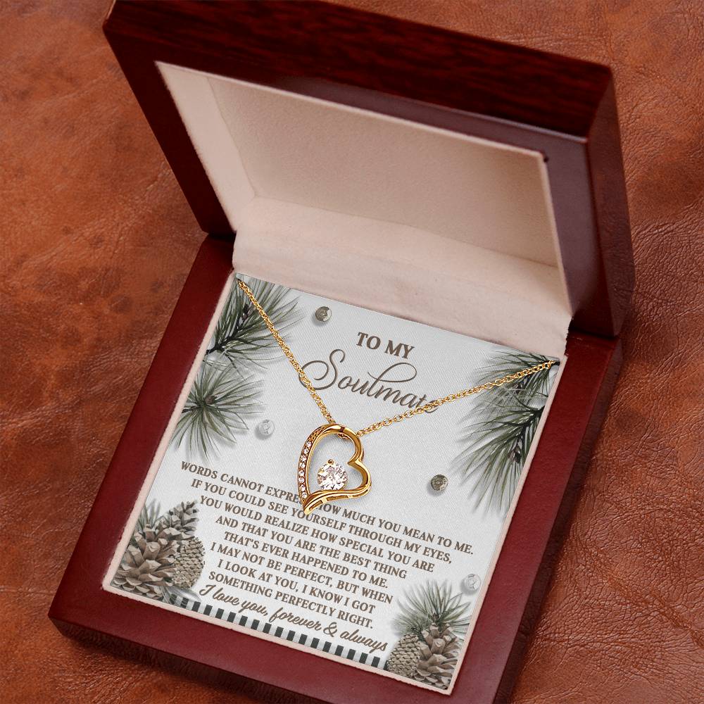 The Soulmate-Perfectly Right - Forever Love Necklace, crafted in a heart-shaped design and featuring a central diamond with a white gold finish, is presented in an elegant wooden box. The lid highlights a heartfelt message set against a wintry background decorated with pine branches and pinecones.