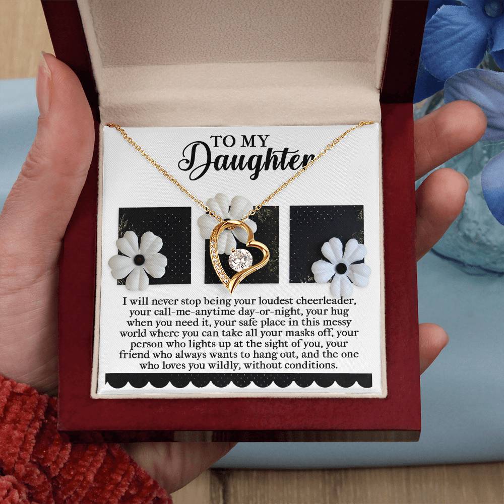 An open red jewelry box reveals a heart-shaped pendant necklace with a white gold finish and earrings decorated with delicate white flowers, held in a hand. Inside the box is an emotional message dedicated to a daughter, epitomizing the charm of the Daughter-Loudest Cheerleader - Forever Love Necklace.