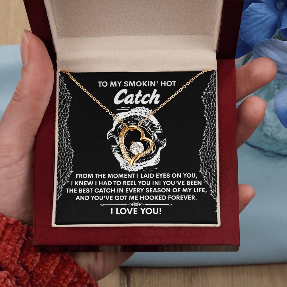 The Soulmate-Got Me Hooked - Forever Love Necklace displays a fish and hook design in a gift box. Against a fishing net patterned background, the message reads, "To my smokin' hot catch... I love you!" It's beautifully crafted with CZ crystal and a shimmering white gold finish.