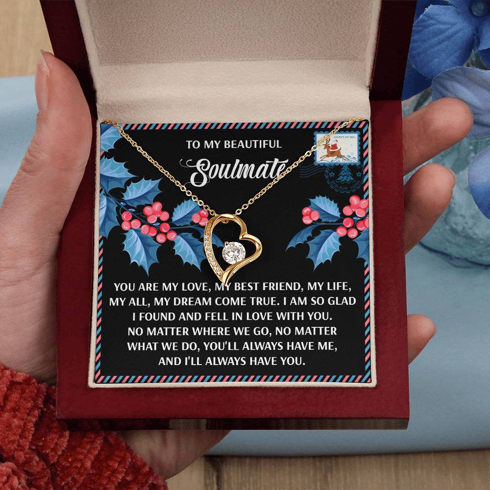 A hand holds an open red jewelry box showing a Soulmate-Fell In Love - Forever Love Necklace, resting on a decorative card with a romantic message. This personalized gift is ideal for expressing eternal devotion.