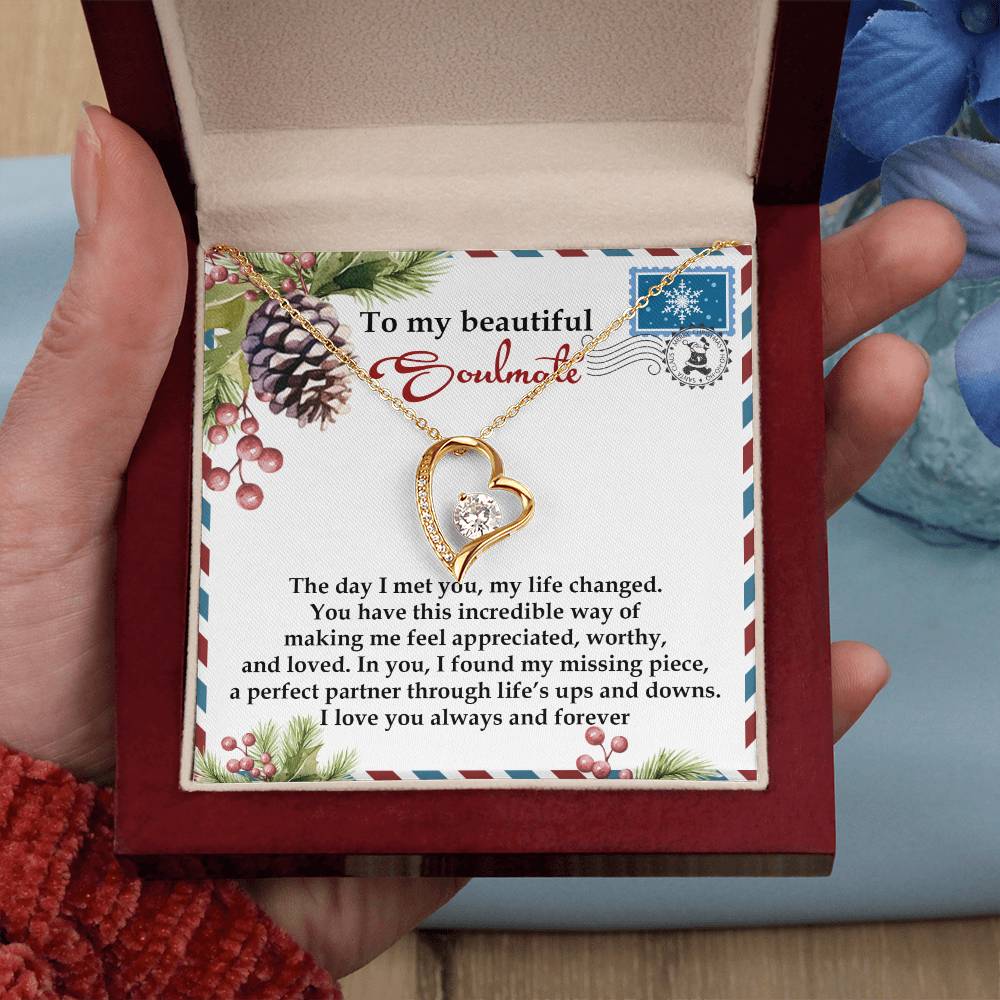 The Soulmate-Perfect Partner - Forever Love Necklace, adorned with a heart-shaped pendant in a gold finish and sparkling cubic zirconia, is packaged in a box that includes a message card expressing love and commitment to your soulmate, featuring floral and pinecone designs.