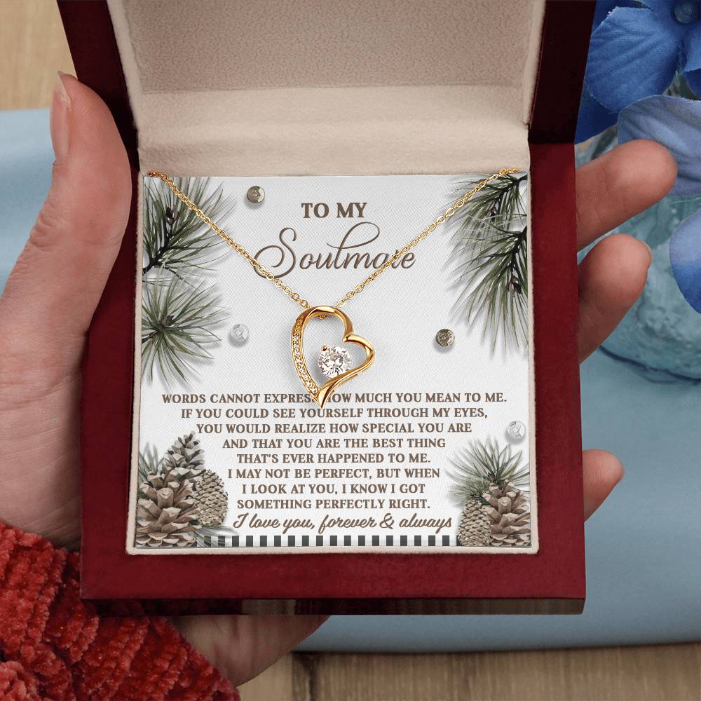 A hand holds an open gift box containing a Soulmate-Perfectly Right - Forever Love Necklace, with a gold heart-shaped pendant and a message card inside, beautifully showcasing it in a stunning yellow gold finish.